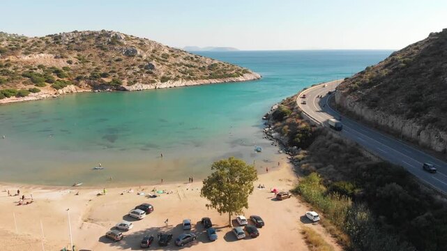 Aerial view of beach and road in Paralia Lomvarda beach near Athens, Greece and seaside. Drone view from above. Sea and coast with sandy beach. Summer destination on the Mediterranean Sea, Europe
