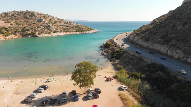 Aerial view of beach and road in Paralia Lomvarda beach near Athens, Greece and seaside. Drone view from above. Sea and coast with sandy beach. Summer destination on the Mediterranean Sea, Europe
