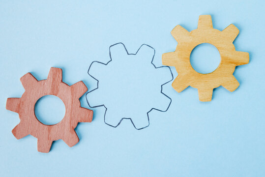 Missing gear wheel concept with wooden cogwheels and drawn outline on blue background. Business mechanism banner with copy space representing vacant position and recruitment process.