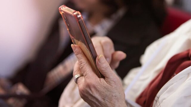 Slow motion senior Taiwanese woman uses a smartphone inside the metro, showing older adult adaptation to new technology, digital communication, public transportation and city life