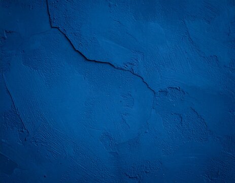 Deep blue textured backdrop of painted wall with rough, uneven surface and a prominent diagonal crack running across