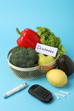 Diabetes. Fresh products in basket, digital glucometer, pen and lancets on light blue background