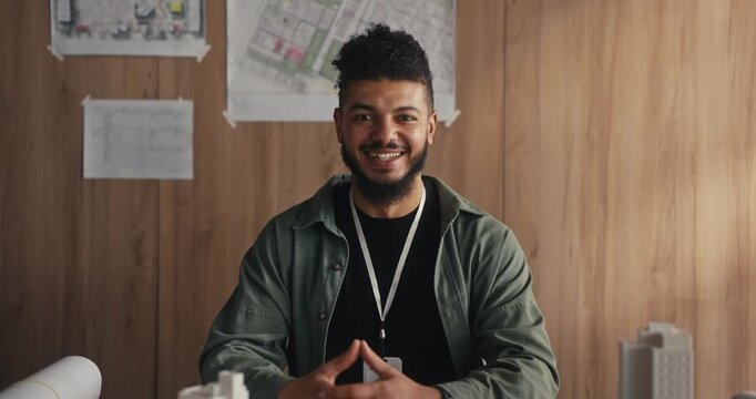 Man shares thoughts on architecture and city planning while seated at a table with design materials in an office