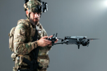 Fototapeta premium Tactical soldier operating unmanned aerial vehicle with remote controller. Concept military UAV technology, communication and surveillance. 