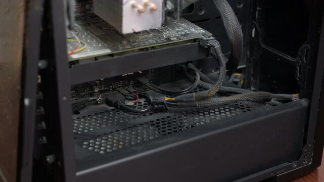 Cleaning dusty computer components with vacuum cleaner. Detail of a technician's hand vacuuming accumulated dust and dirt from inside a personal computer case, cleaning the components for proper