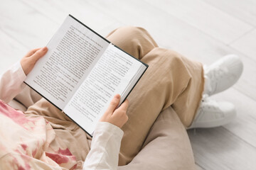 Naklejka premium Beautiful young woman reading book and sitting on beanbag chair in bedroom, top view