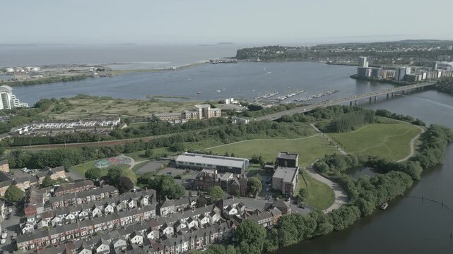 4K Aerial Drone Shot Flying Toward Cardiff Bay Barrage, Hamadryad Park,Wetlands Reserve, Cardiff Yacht Club, and Cardiff, Wales, United Kingdom, with Car Passing Over Cardiff Bay Link Bridge - D-LOG