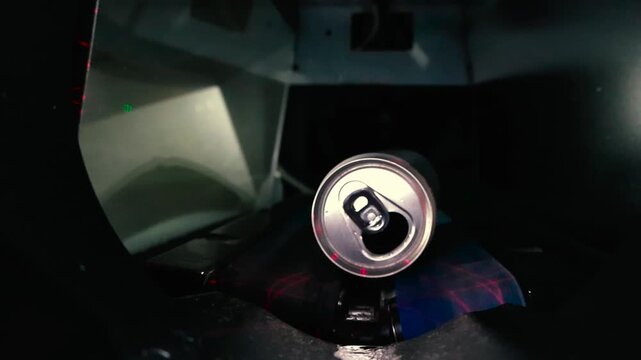 Close up of multiple aluminum cans being inserted into a reverse vending machine for recycling, with the internal mechanism scanning and accepting the empty beverage containers for a deposit return