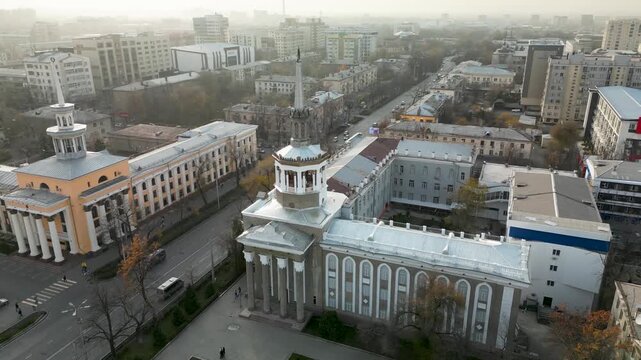Soviet-era monumental architecture in Bishkek, Kyrgyzstan. Symmetrical educational buildings with classical columns and rotunda elements along a wide urban avenue.