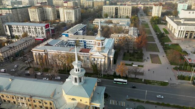 Soviet-era monumental architecture in Bishkek, Kyrgyzstan. Symmetrical educational buildings with classical columns and rotunda elements along a wide urban avenue.
