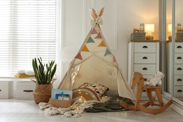 Cute wigwam with fairy lights and toys in stylish child's room © New Africa