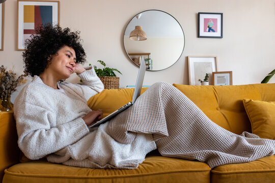 Woman relaxing at home working on laptop