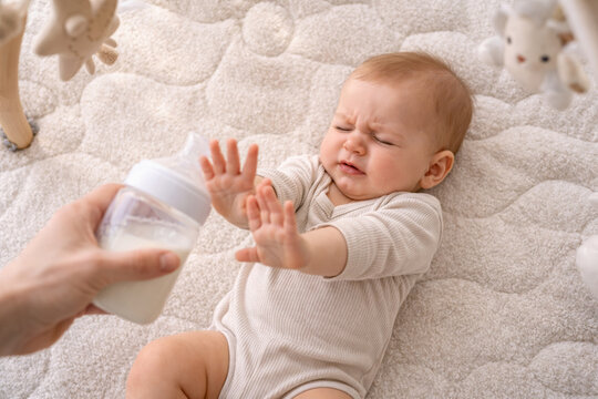 Baby refusing to take milk from the bottle on blanket