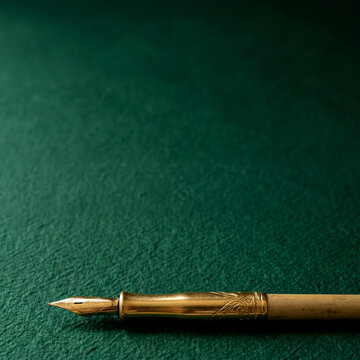 Gold calligraphy pen at bottom with massive emerald paper space