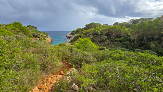 Beautiful landscape of Cala Murta bay with turquoise water and rocky cliffs under cloudy sky in Mallorca, Spain