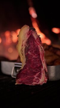 Delicious raw galician blonde beef ribeye steak grilling over hot charcoal. Premium quality red meat cooking on a barbecue for a fine dining meal