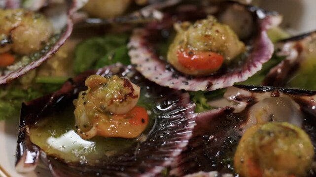 Delicious gourmet dish of grilled scallops in shells. A close up view of fresh seafood seasoned with sauce and served with lime slices
