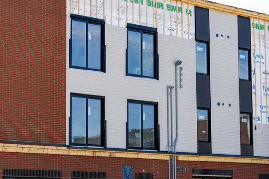 La Tuque, Quebec, 23 May 2026 : Exterior of a multi-story building under construction with brick, siding, and exposed framing with BMR and Tyvek HomeWrap.