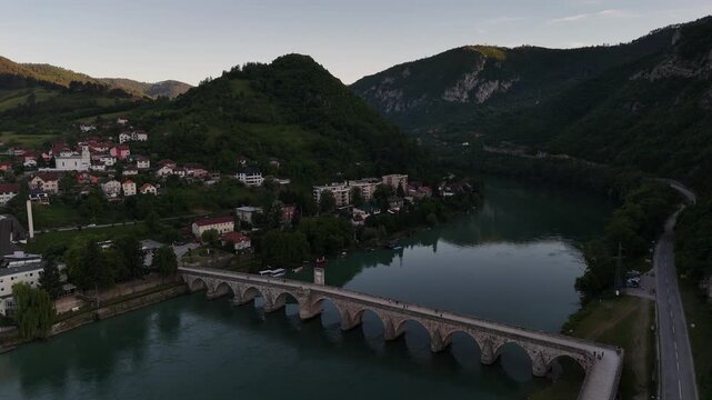 Cinematic Drone View of Historic Mehmed Pasa Sokolovic Bridge at Sunset, Backward Tracking Aerial Shot of UNESCO Landmark and Drina River in Visegrad Bosnia, 4K