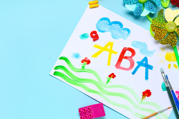 Naklejka premium Children's creative learning activity with colorful ABC painting, art supplies, and educational toys on blue background
