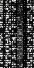 Fototapeta premium Monochromatic high rise building facade at night with glowing windows creating a symmetrical urban geometric pattern