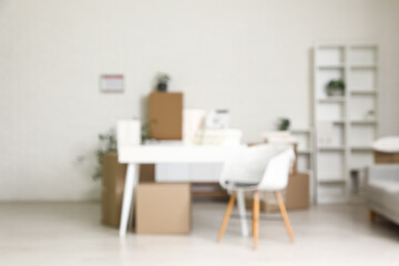 Fototapeta premium Blurred background of modern office or home interior with desk, chair, and moving boxes, new beginnings