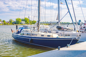 Obraz premium Sailboats docking at pier on sunny day with bridge in background