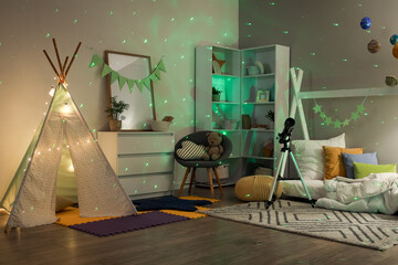 Cozy children's playroom with teepee tent, telescope, and green starry night projector lights © Pixel-Shot