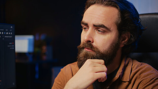 Software technician puzzled in front of computer screen while writing complex code, thinking of solution. IT expert feeling confused while trying to solve database bugs. close up.