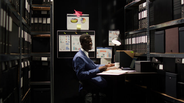 Detective inspector with abilities in criminal investigation, surrounded by case files and evidence, smiles confidently at camera.