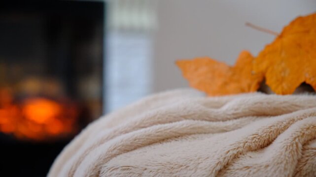 Fireplace and fluffy warm beige blanket. Autumn whispers through the window, while inside, warmth and comfort reign supreme. Snuggled under a soft, warm blanket by the crackling fireplace
