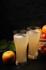 Fototapeta premium Glasses of fresh apple kvass and fruits on black background