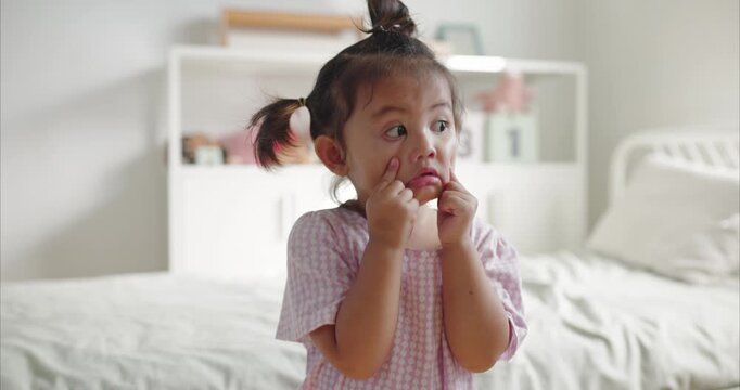 Cute Asian Toddler Girl with Pigtails Making Funny Face  with Eye Contact, Happy Daughter Having Quality Time with Mother in Cozy Domestic BedRoom