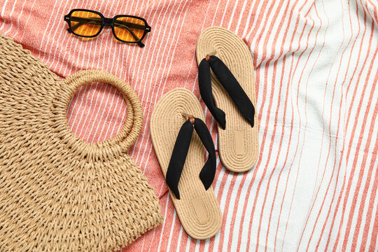 Flip flops with straw bag and sunglasses on textile background