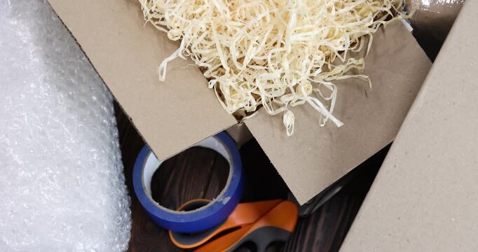 Different packaging materials on wooden table, above view. Camera moving around