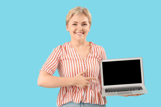 Happy young female programmer pointing at laptop on blue background