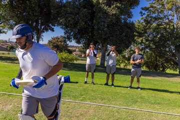 Obraz premium Male cricket team clapping while male batter running left wearing helmet past rope line, copy space