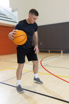 Orange basketball resting on polished hardwood court with colorful painted lines and bench