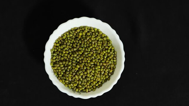 organic green mung beans in white bowl isolated on black background