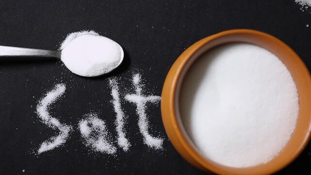 refined table salt crystals arranged with spoon and bowl for seasoning concept