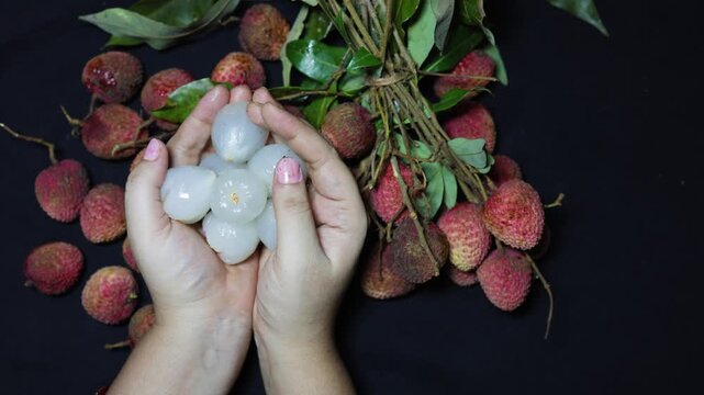 fresh peeled lychees in hands surrounded by ripe tropical fruit collection