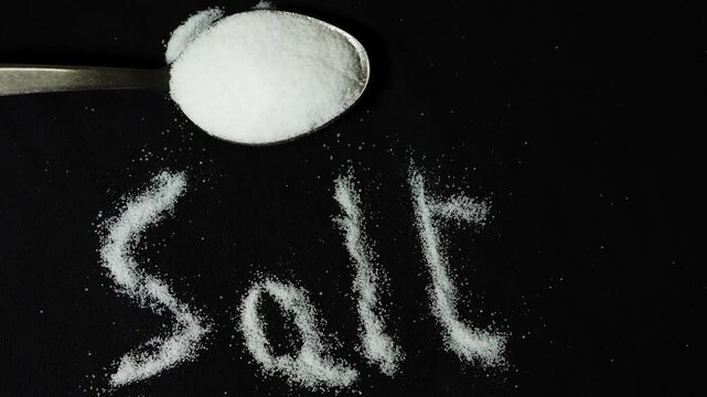 culinary seasoning ingredient featuring white salt crystals on black surface