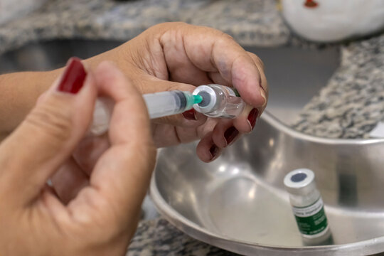 Close-up of a healthcare worker's hands preparing a vaccine syringe from a vial at a public health clinic (UBS) in Marilia, Sao Paulo state, Brazil. 