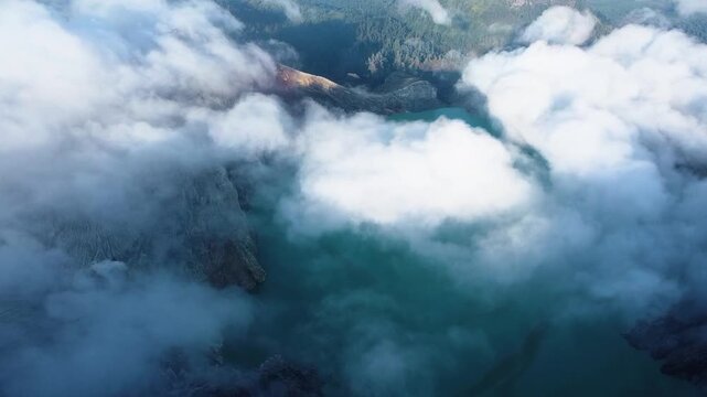 Aerial view flying over ijen volcano crater lake through clouds