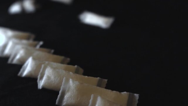 Macro view of white snus nicotine pouches arranged in a diagonal row on a black surface, representing a modern smokeless alternative to traditional tobacco products and smoking