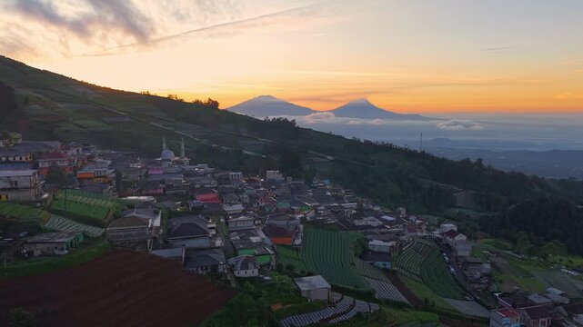 Scenic aerial of hillside village at sunrise, vibrant landscape with terraces and glowing sky. Nepal Van Java, Indonesia.