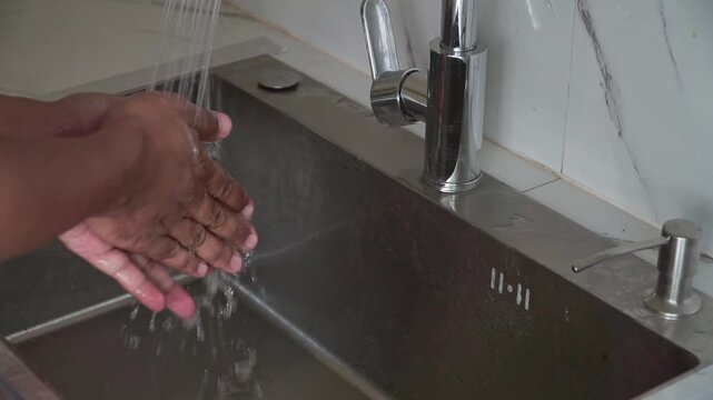 Hands being scrubbed and rinsed at a sink. Perfect for healthcare, hygiene awareness, germ removal, and wellness projects.