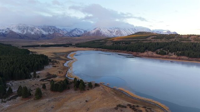 Slow drone flyover above Laguna La Zeta near Esquel, Chubut, Argentina, revealing Andean lake shoreline, Patagonian forest, wetlands, and snow covered mountain range.
