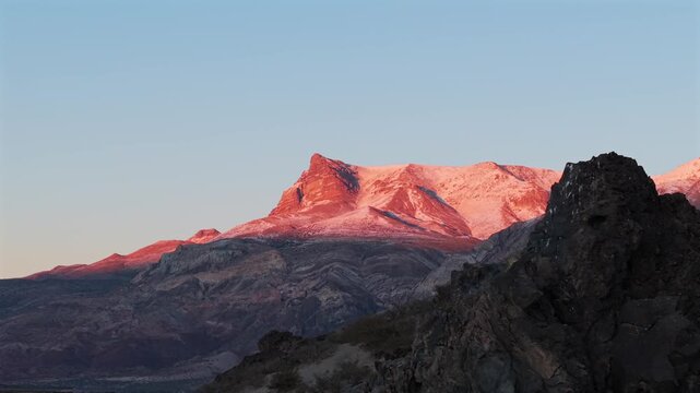 Pay&uacute;n Matr&uacute; volcano in La Payunia Provincial Reserve, Malarg&uuml;e, Mendoza Argentina illuminated by sunrise light above volcanic canyon formations and eroded Andean foothill terrain lateral drone slide