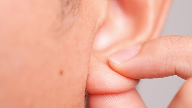 A hand gently massaging an earlobe conveys self-care, relaxation, and mindfulness, while also representing stress relief, sensory awareness, personal wellness, and a moment of soothing comfort.
